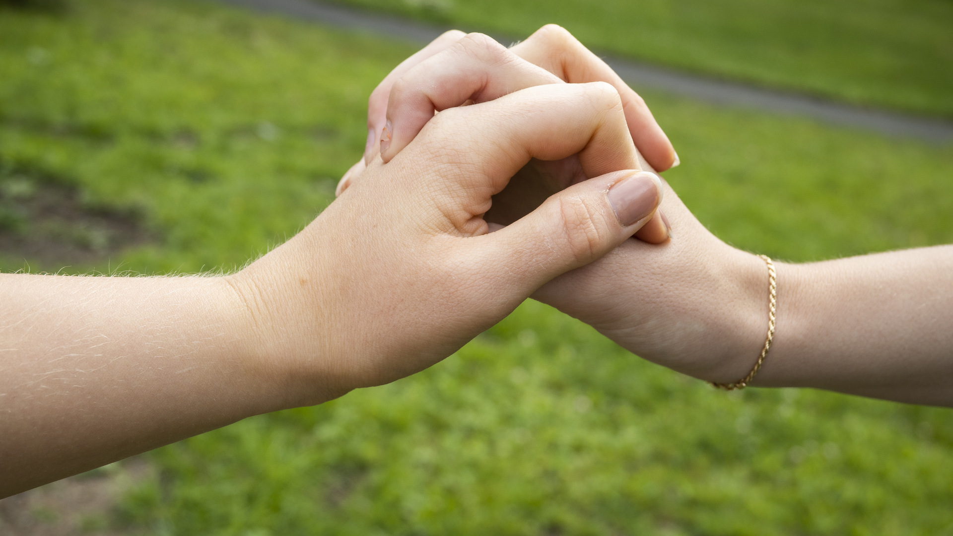 Två händer som håller i varandra mot en grön bakgrund